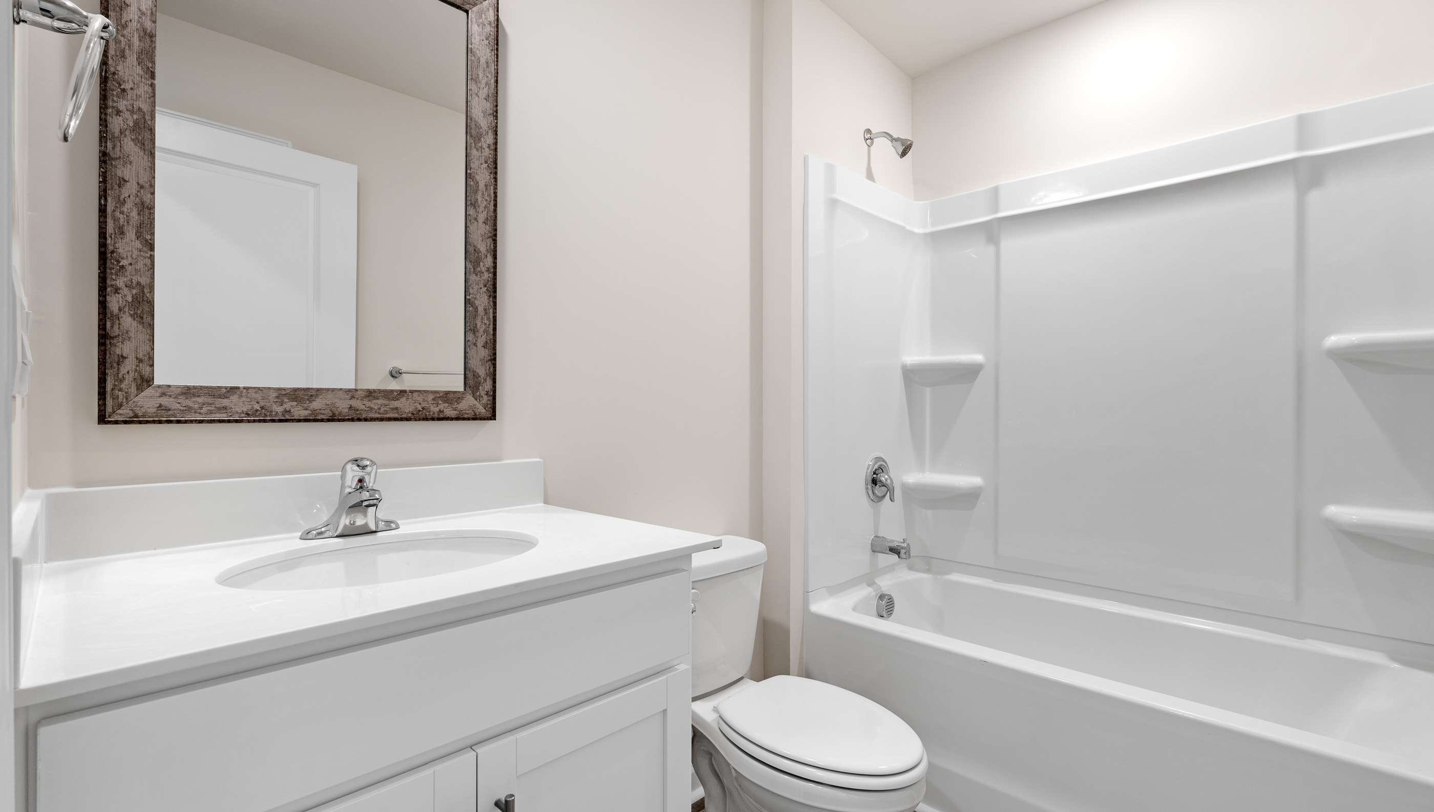 Hallway bathroom with vanity and tub.