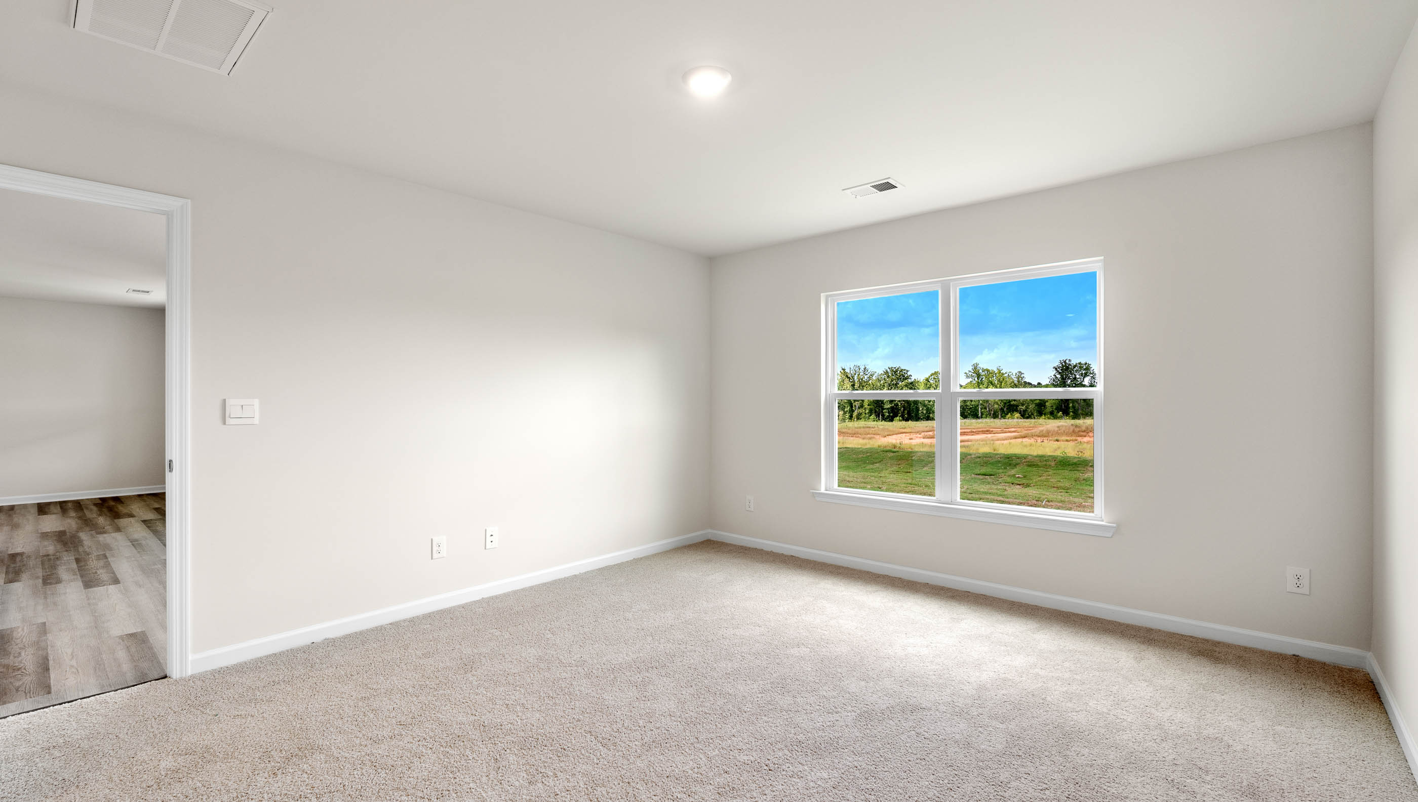 Primary bedroom with carpet and window.