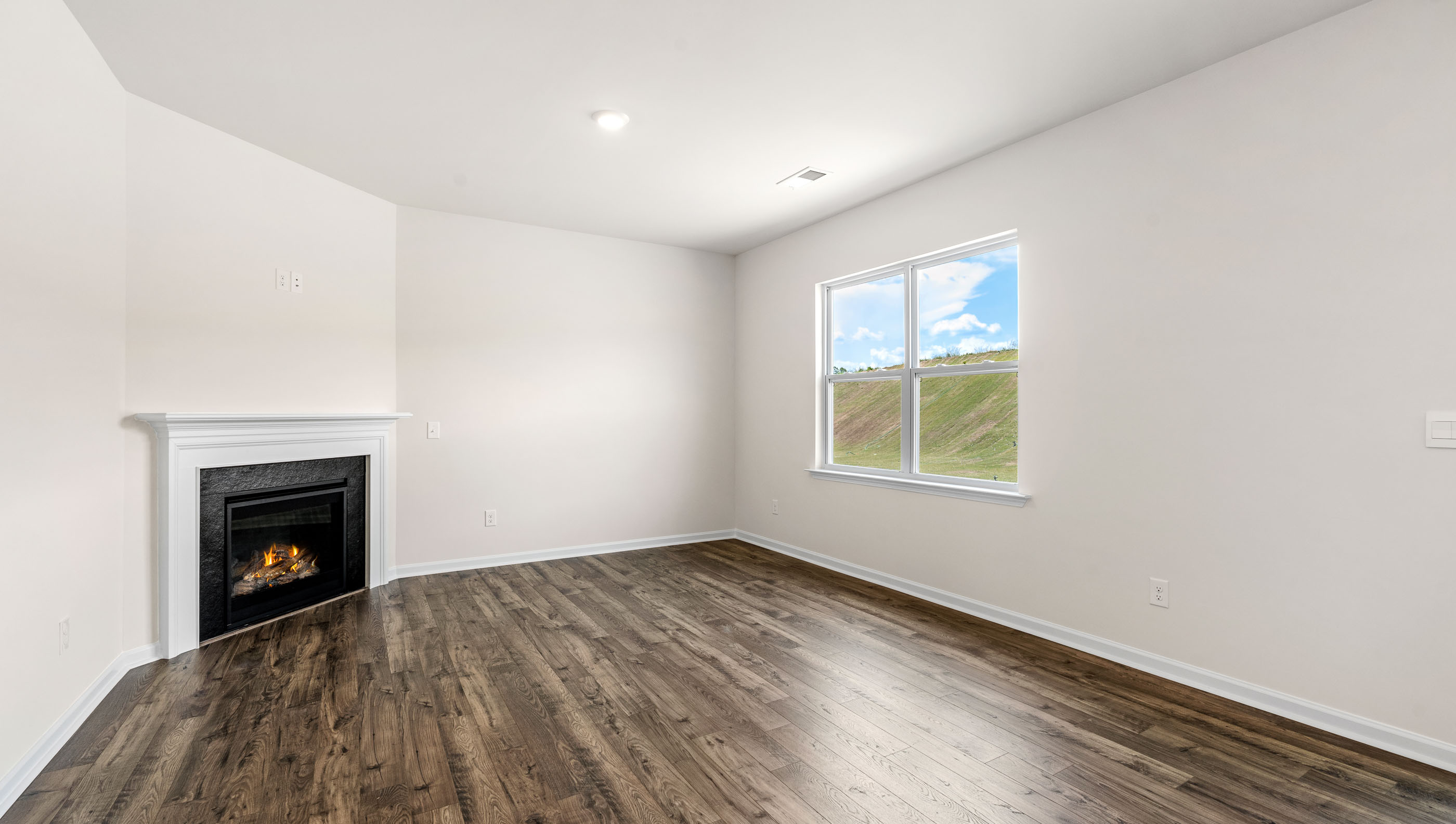 View of great room with gas log fireplace and large windows.