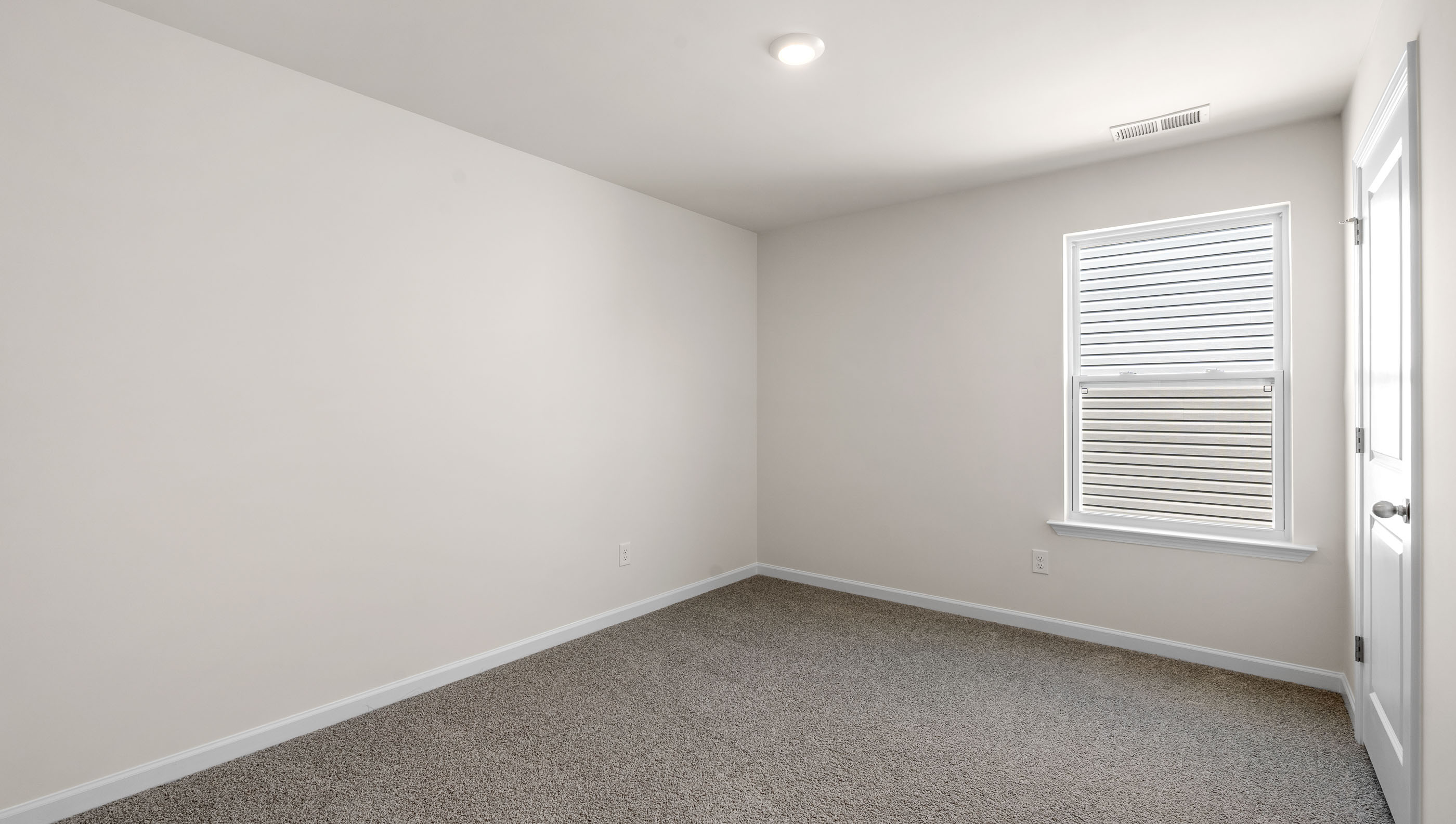 Bedroom with large window and carpet.