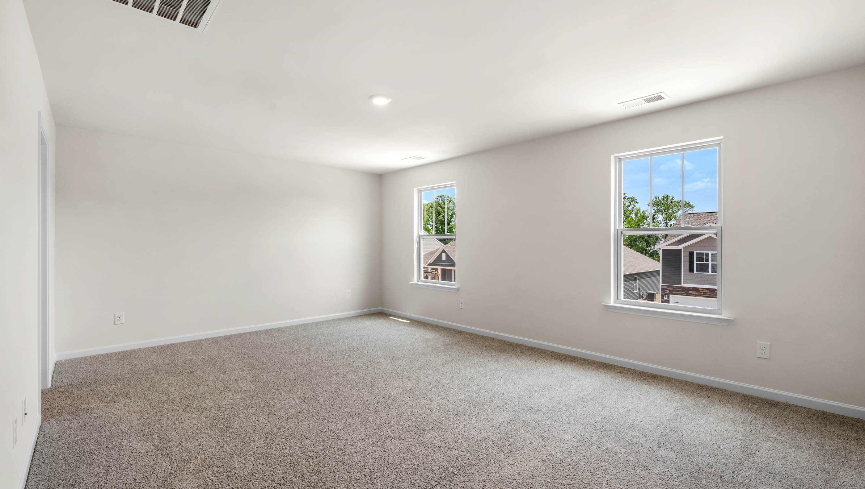 View of large primary bedroom and two large windows allowing in natural light.