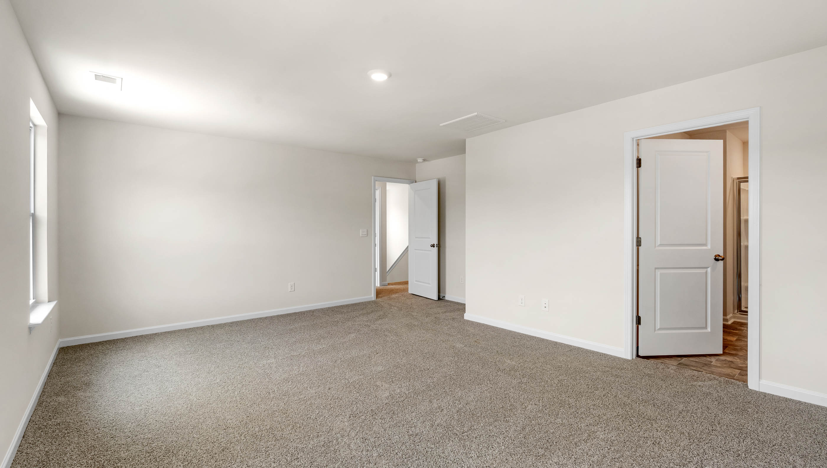 Primary bedroom with recessed lighting and carpet.
