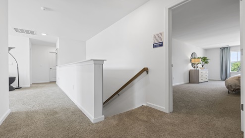 Top of stairs area with carpet and view of bedroom.