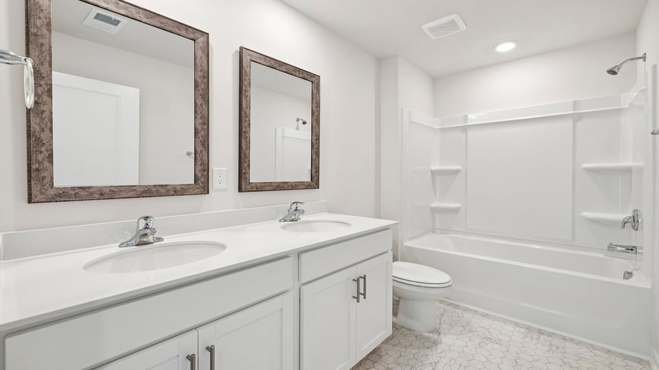 Hall bathroom with dual sink vanity and combination shower / tub.