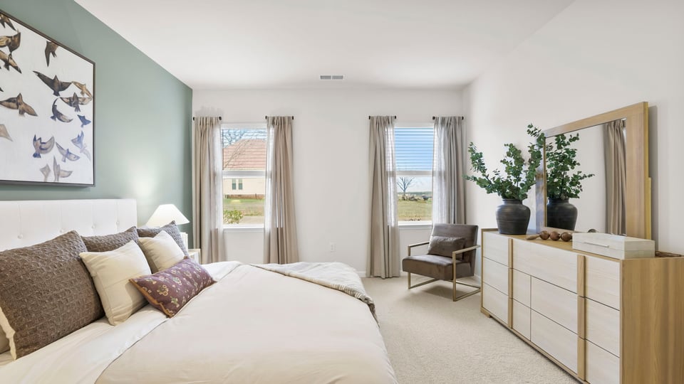 Primary bedroom with carpet and window.