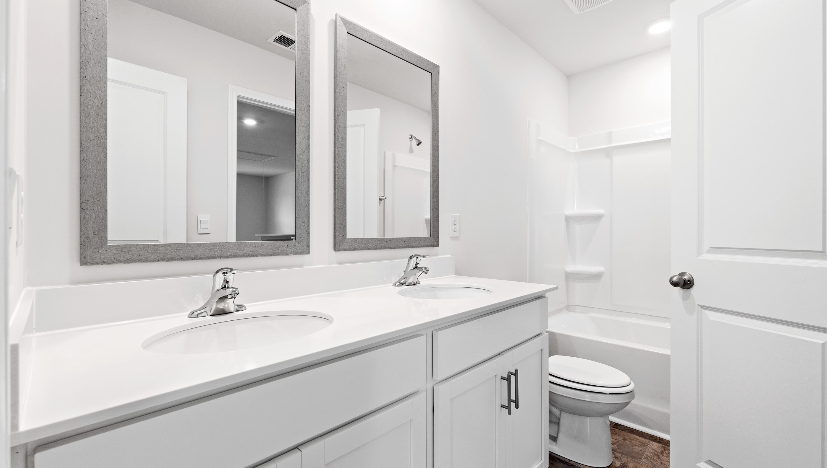 Hallway bathroom with dual sink vanity and tub.