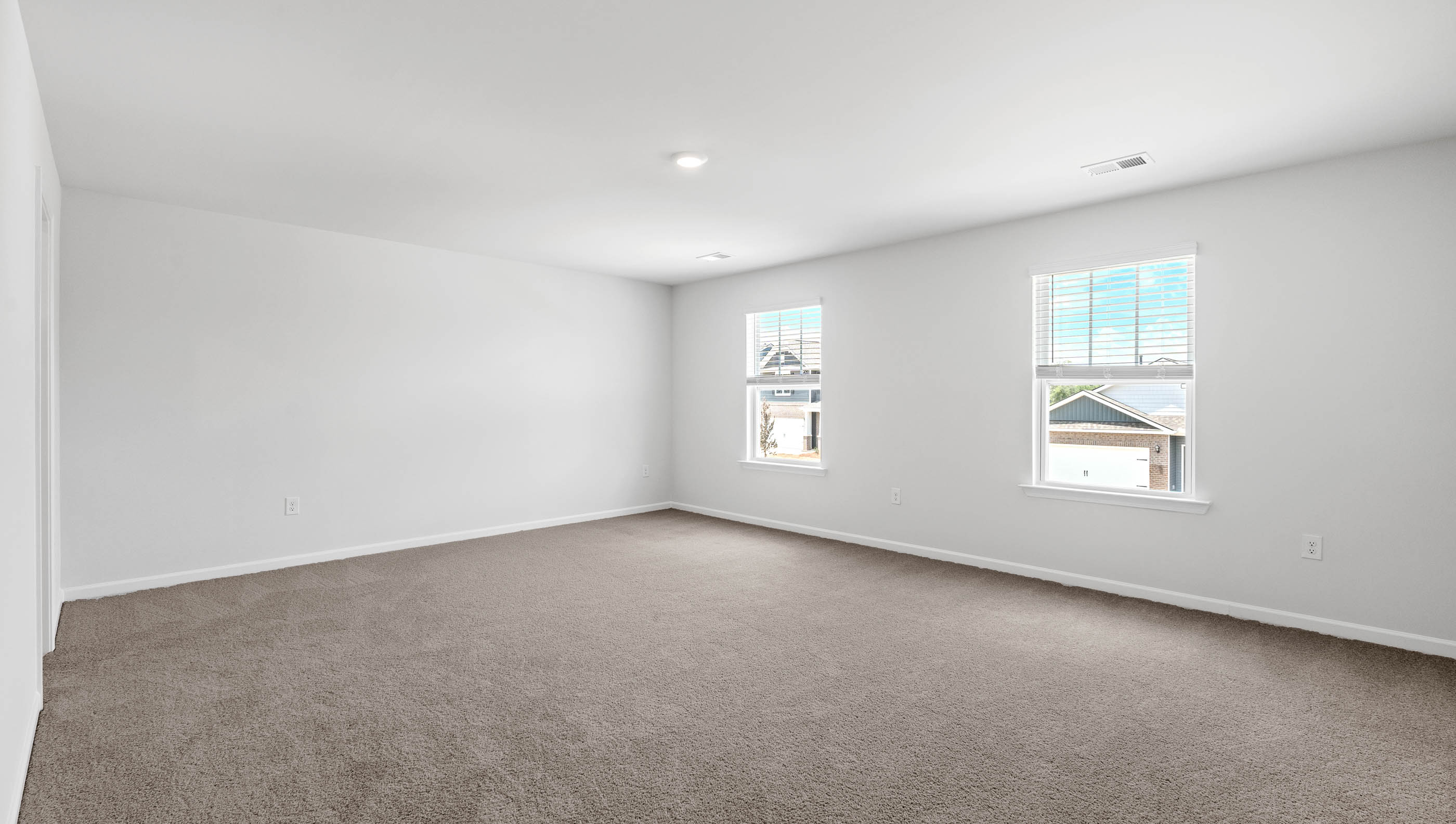 Primary bedroom with carpet and window.