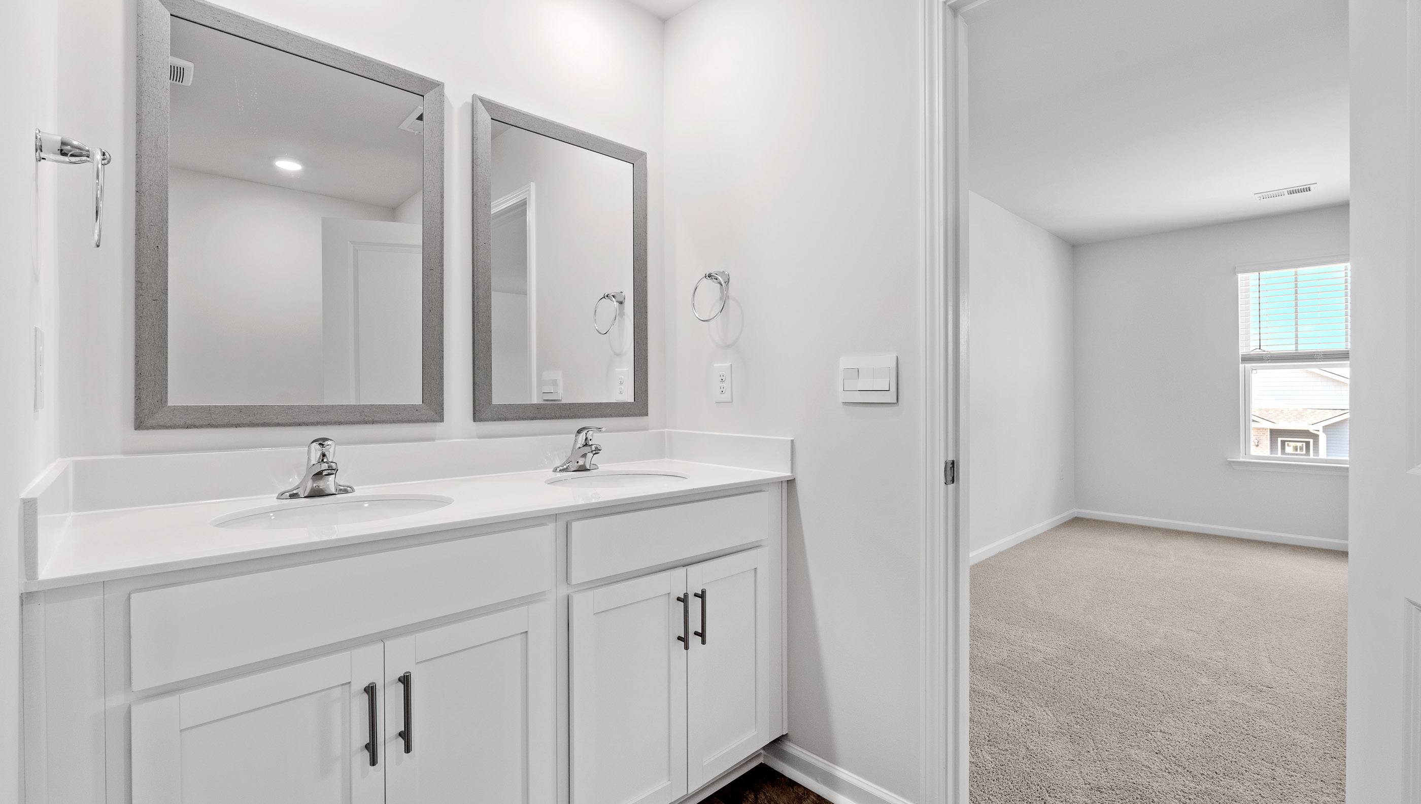 Primary bathroom with dual sink vanity and mirrors.