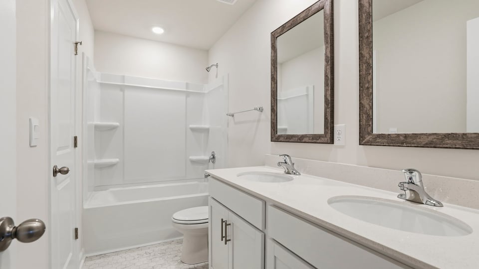 Hall bathroom with dual sink vanity and combination shower / tub.