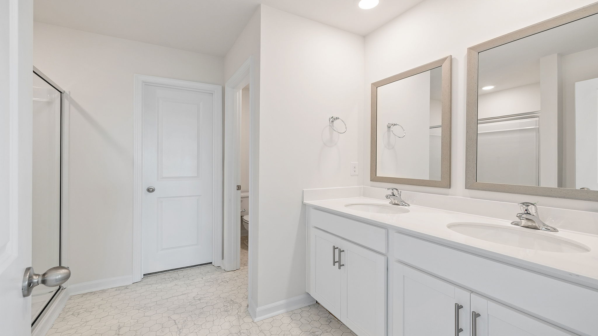 Primary bathroom with dual vanity and walk in shower.