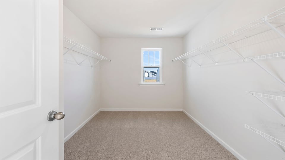 Walk in closet with hanging shelves and window.