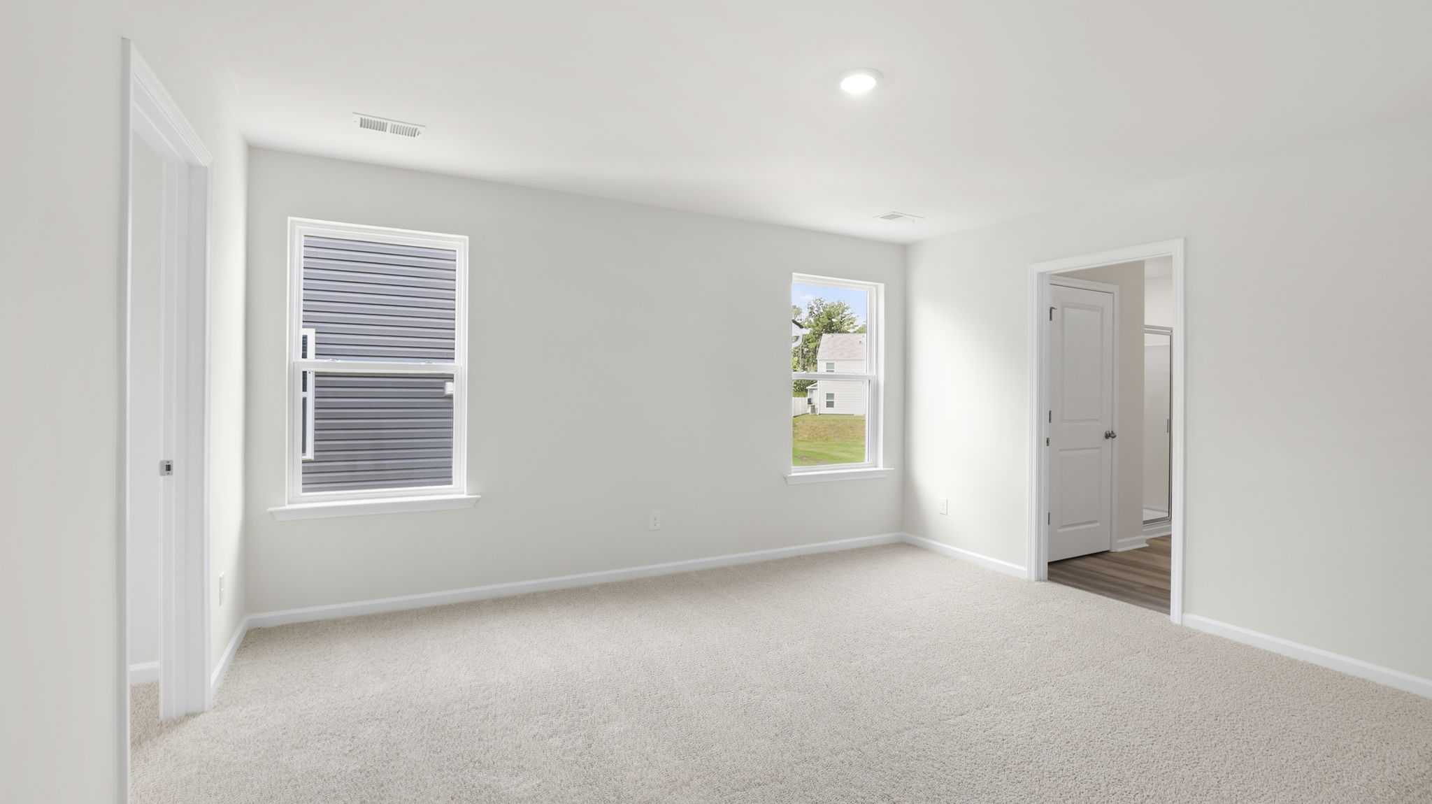 Primary bedroom with window and carpet.