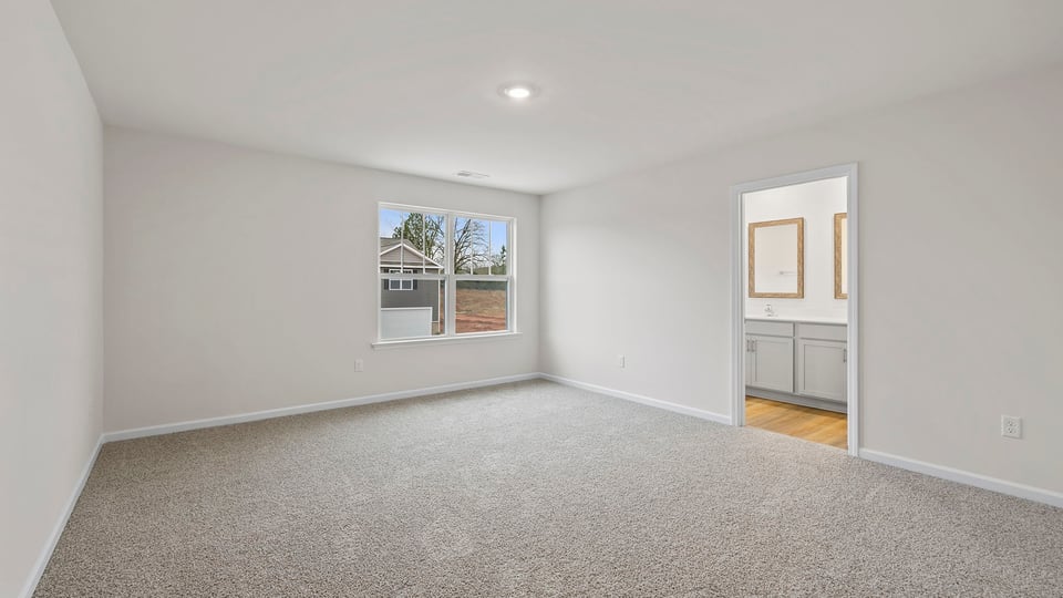 Primary bedroom with large window and carpet.
