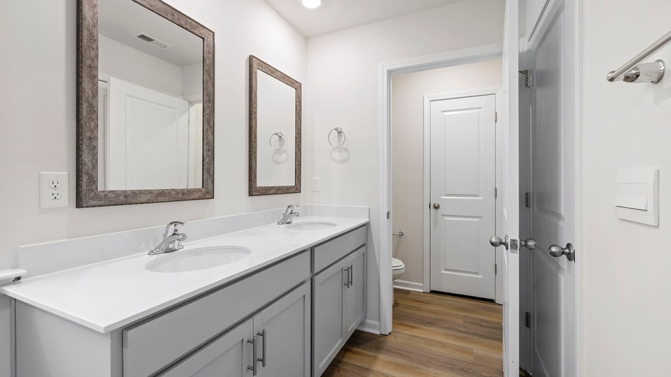 Primary bathroom with dual sink vanity and mirrors.
