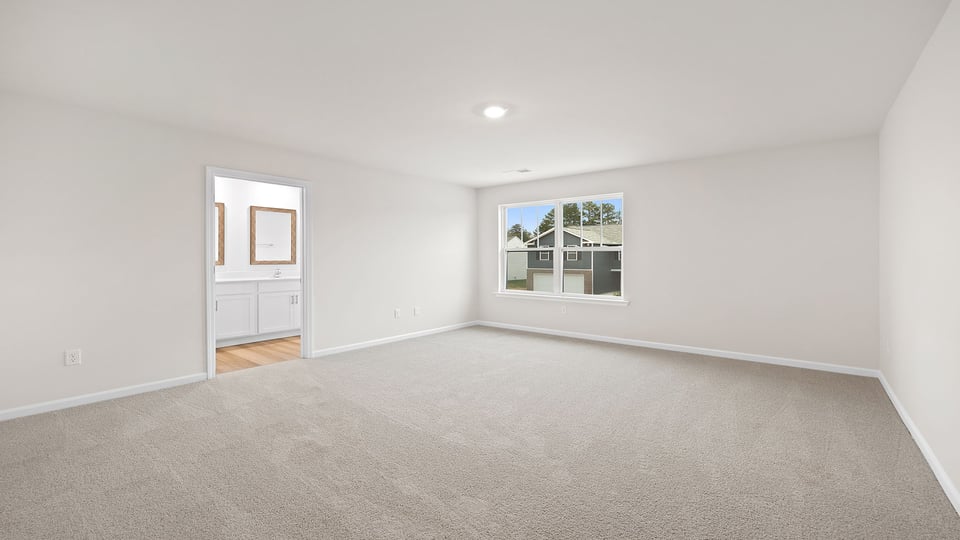 Primary bedroom with large windows and carpet.