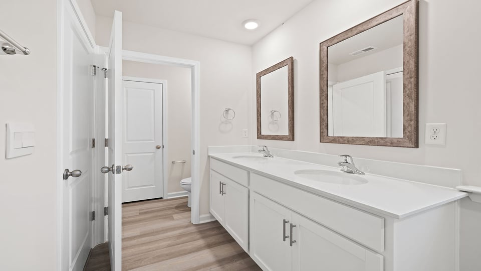 Primary bathroom with dual sink vanity and mirrors.
