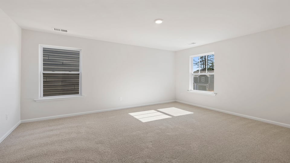 Primary bedroom with windows and carpet.