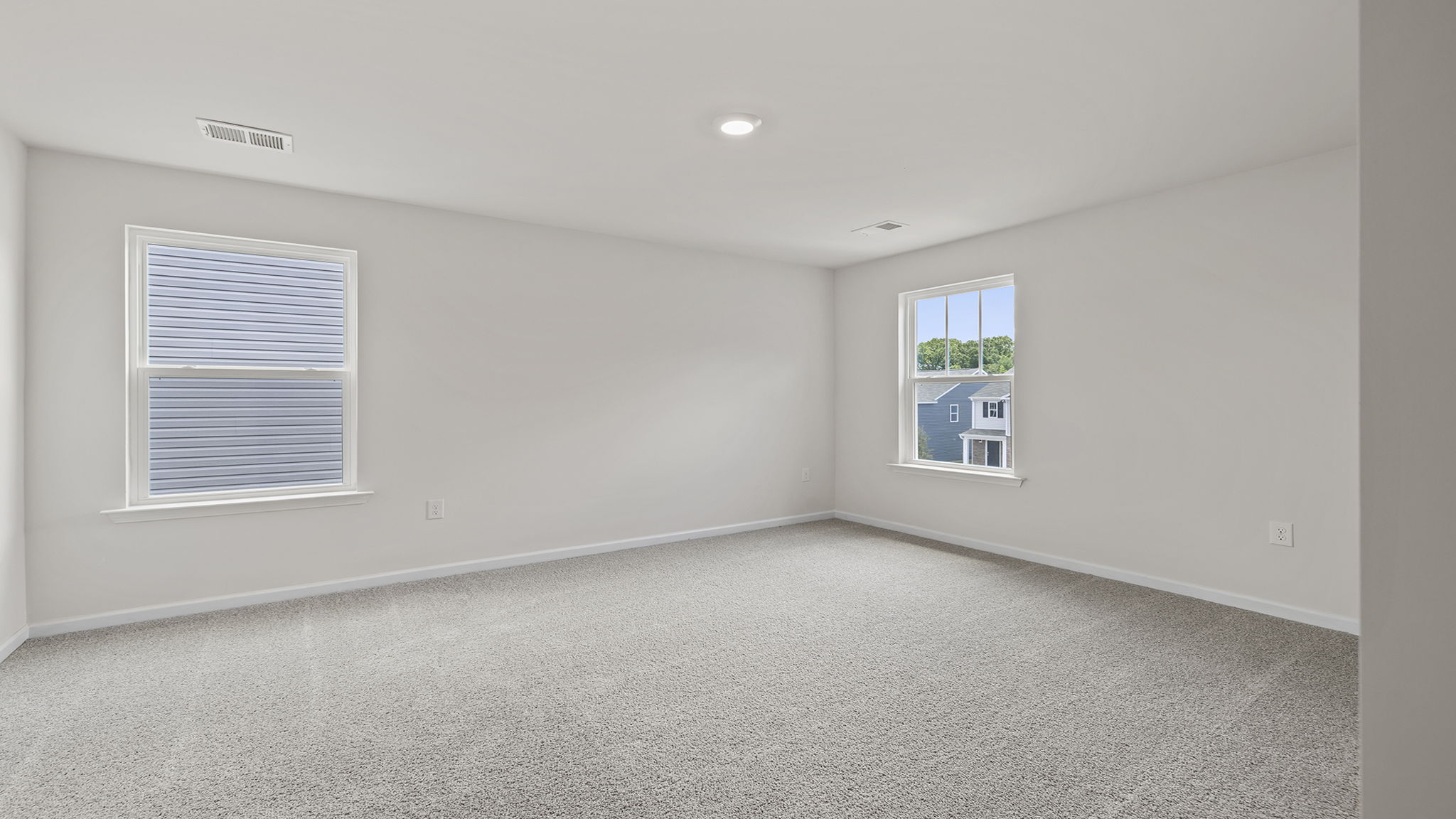 Primary bedroom with windows and carpet.