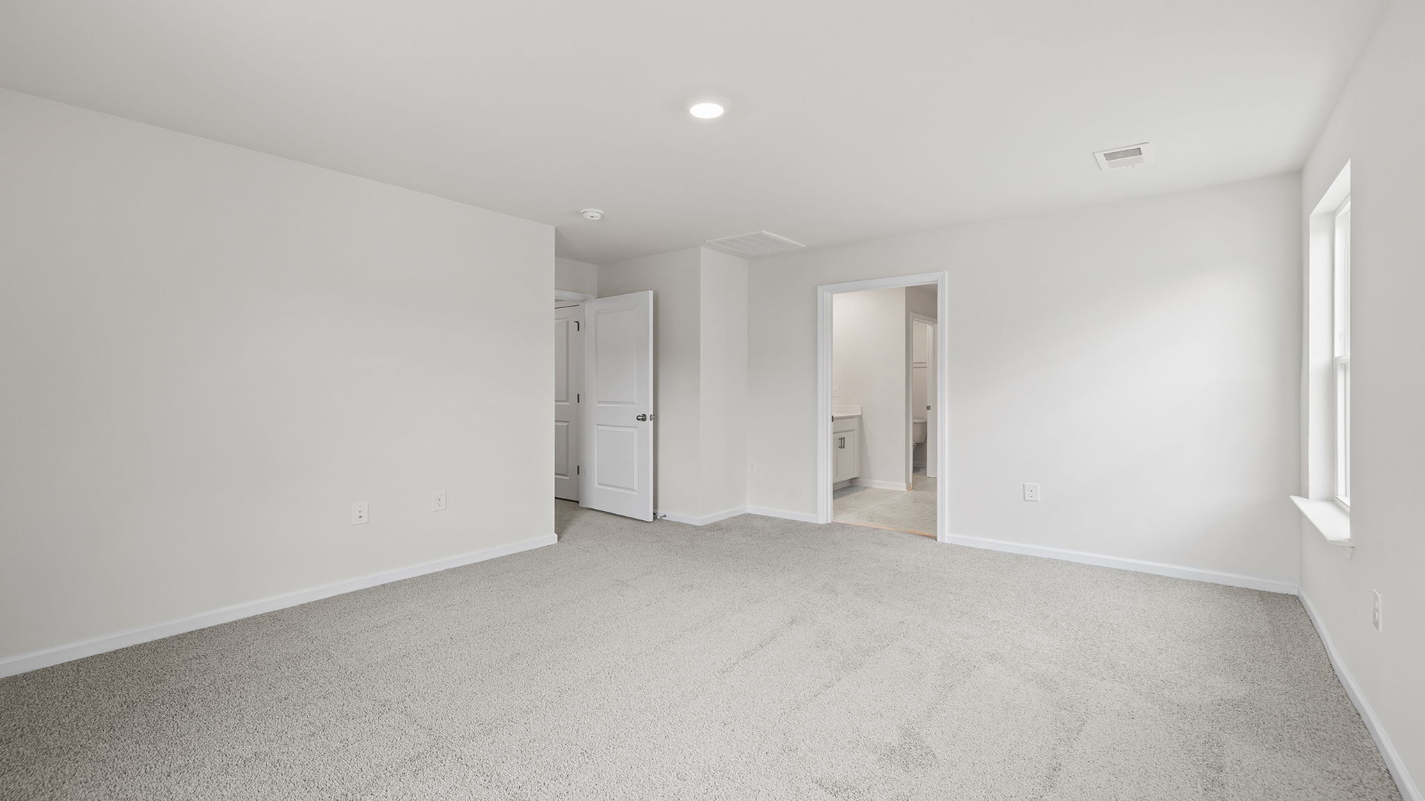 Primary bedroom with windows and carpet.