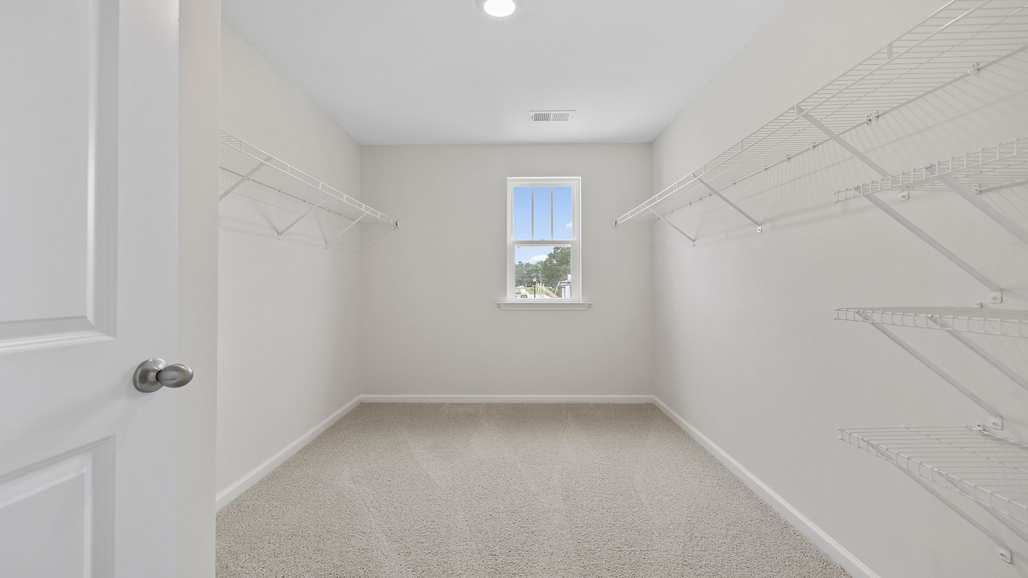 Primary closet with carpet and window.