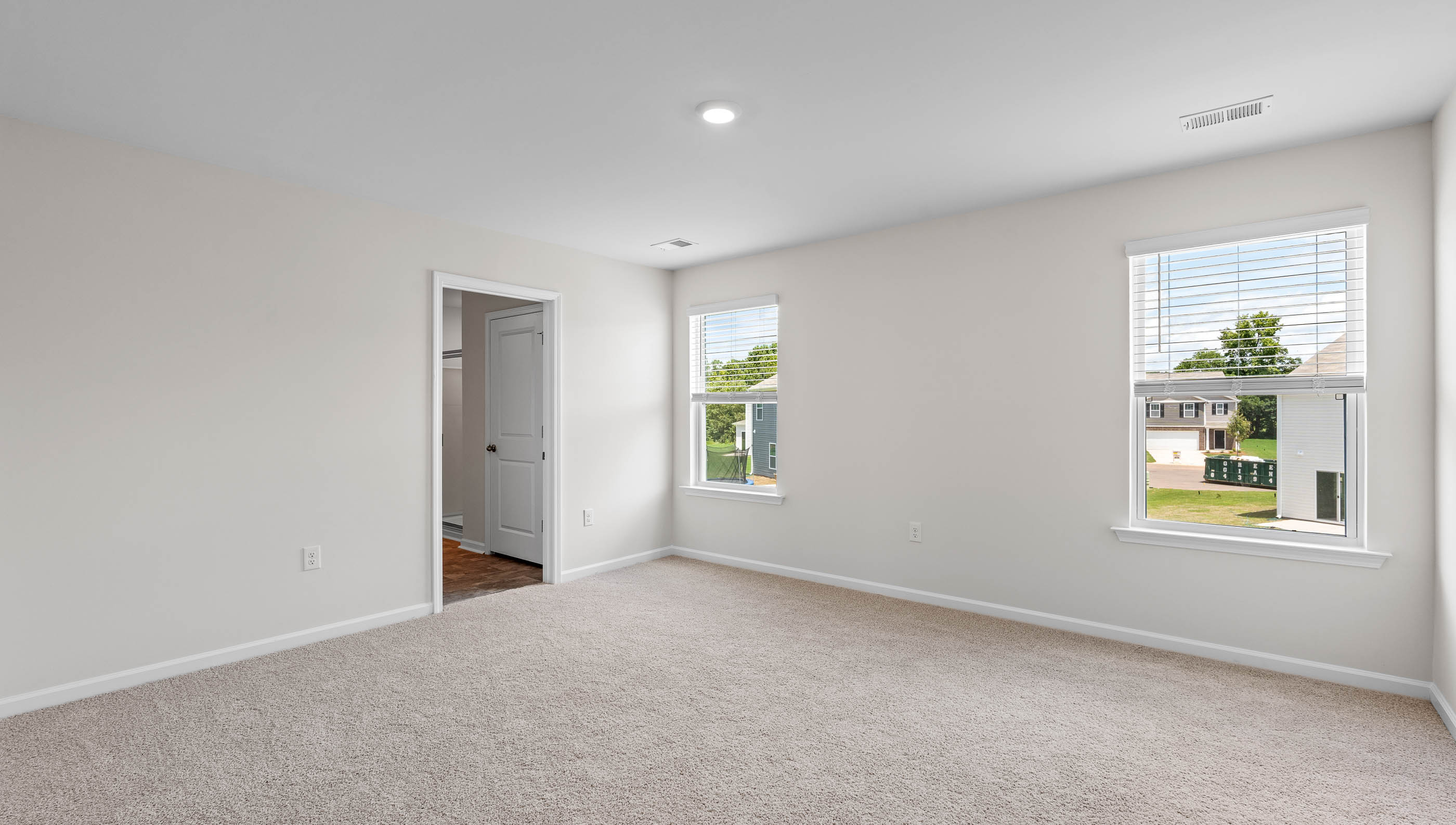 Primary bedroom with windows and carpet.