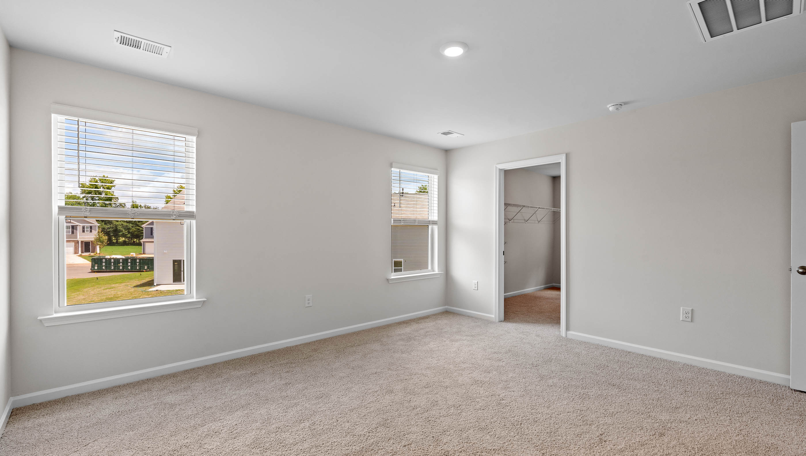Primary bedroom with windows and carpet.
