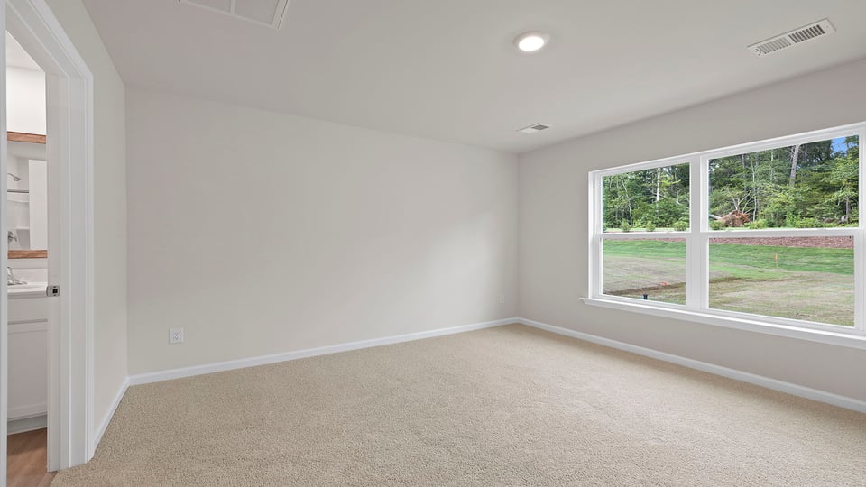 Primary bedroom with carpet and windows.