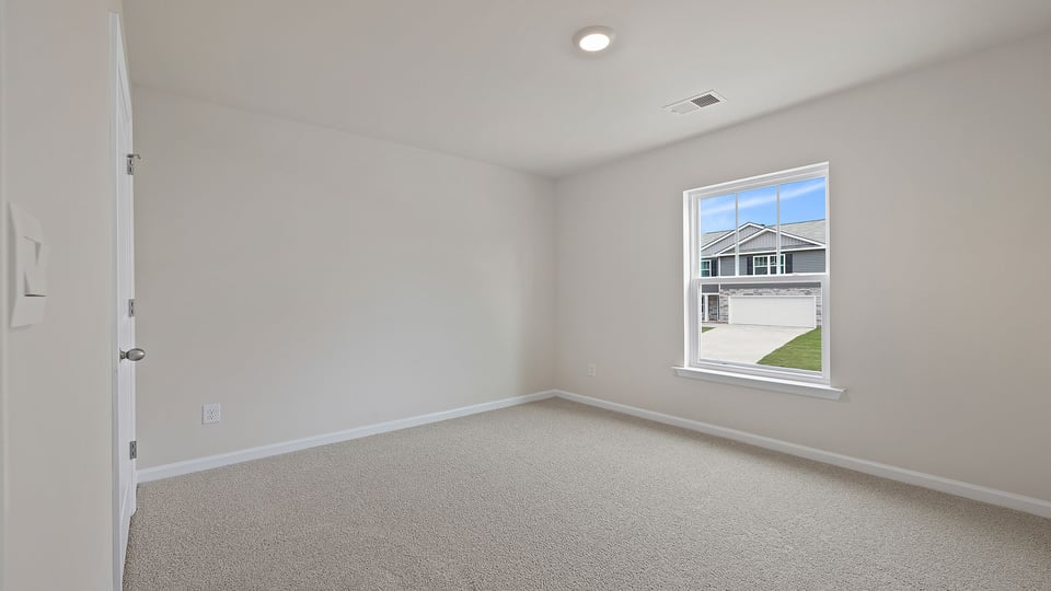 Primary bedroom with carpet and windows.