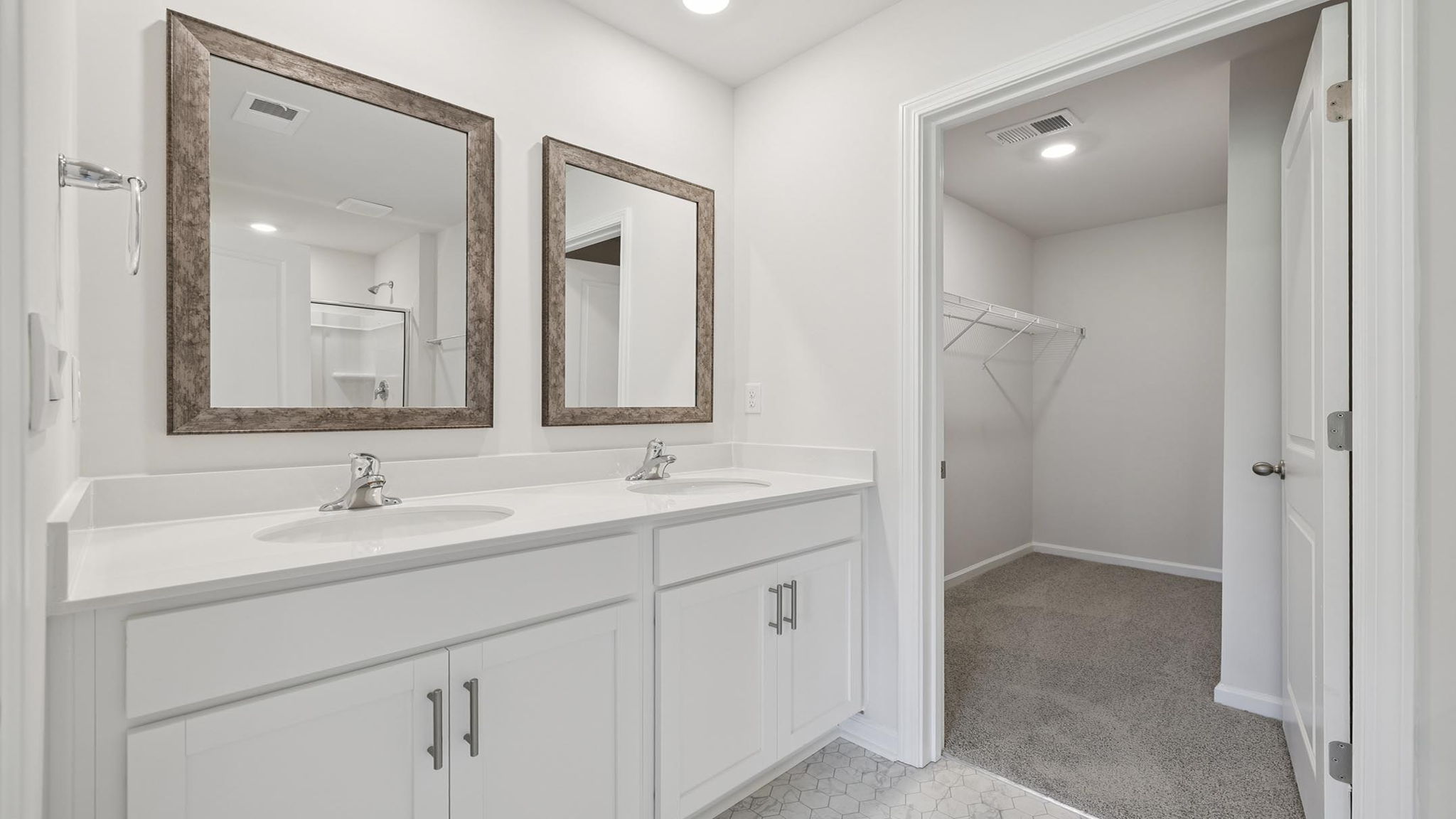 Primary bathroom with dual sink vanity and mirrors.