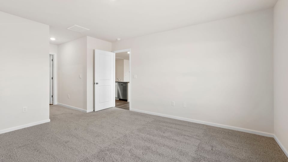 Primary bedroom with carpet and window.