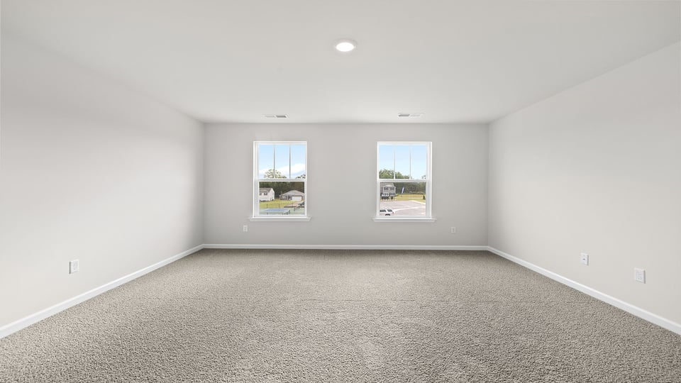 Primary bedroom with carpet and window.
