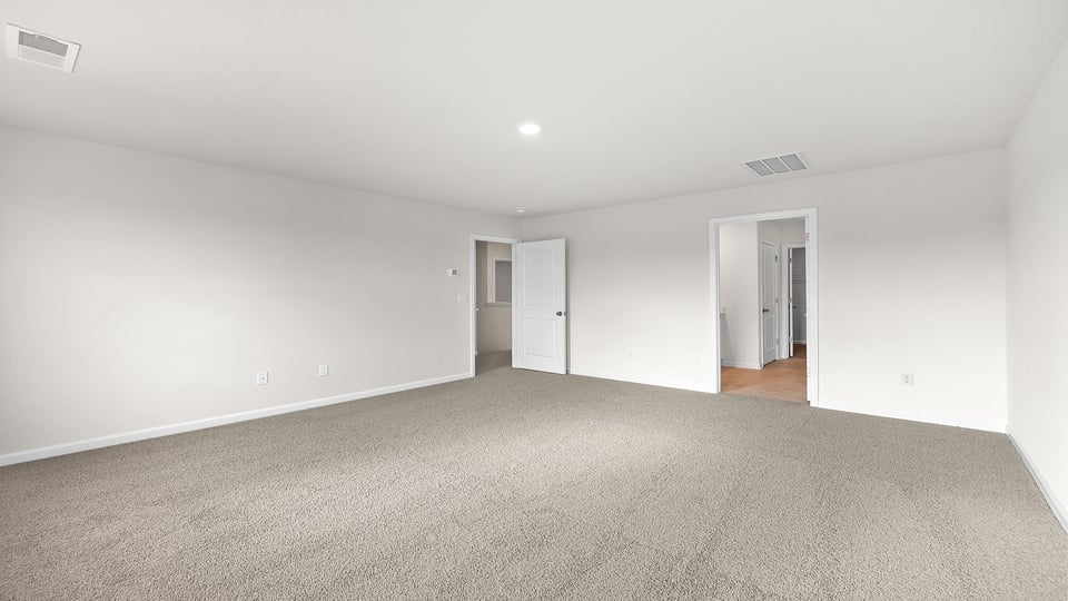 Primary bedroom with carpet and window.