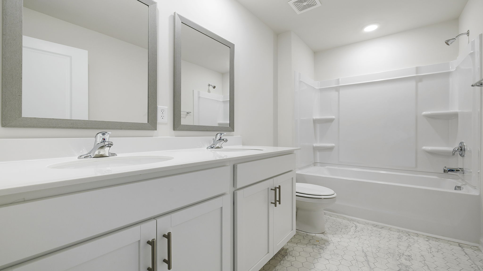 Hall bathroom with dual sink vanity and shower / tub.