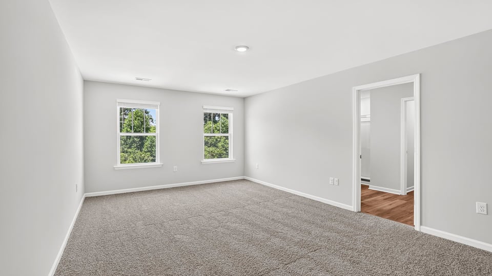 Primary bedroom with carpet and window.