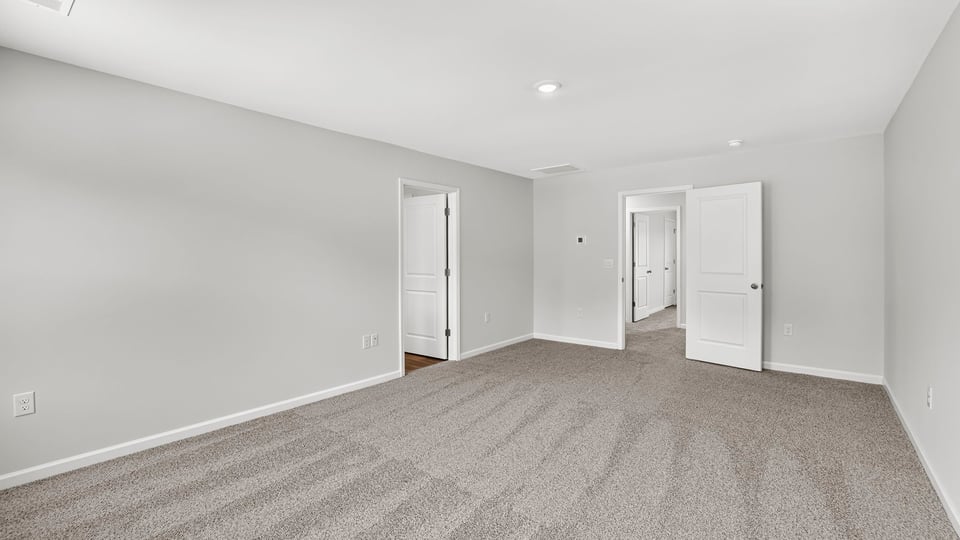 Primary bedroom with carpet and window.
