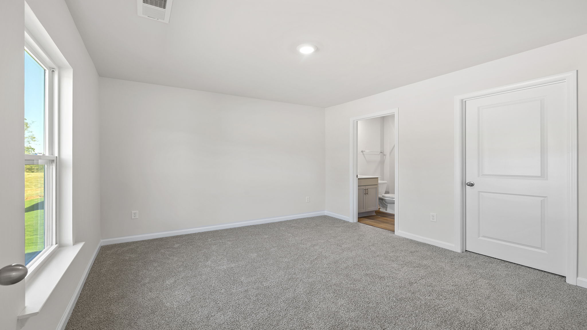 Primary bedroom with windows and carpet.