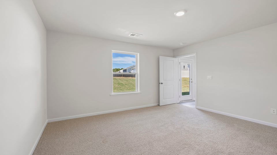 Primary bedroom with carpet and windows.