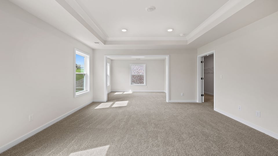 Primary bedroom with carpet and windows.
