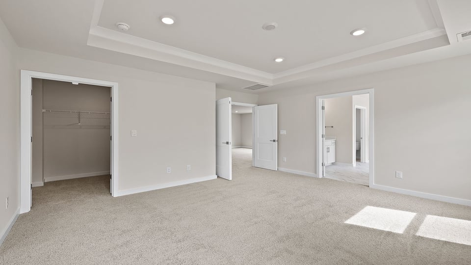 Primary bedroom with carpet and windows.