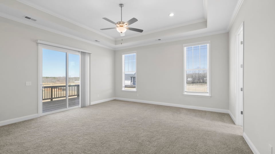 Bedroom with carpet and winsows with doors to patio.