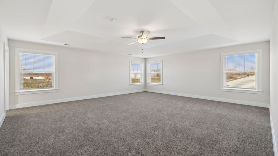 Primary bedroom with carpet and windows.