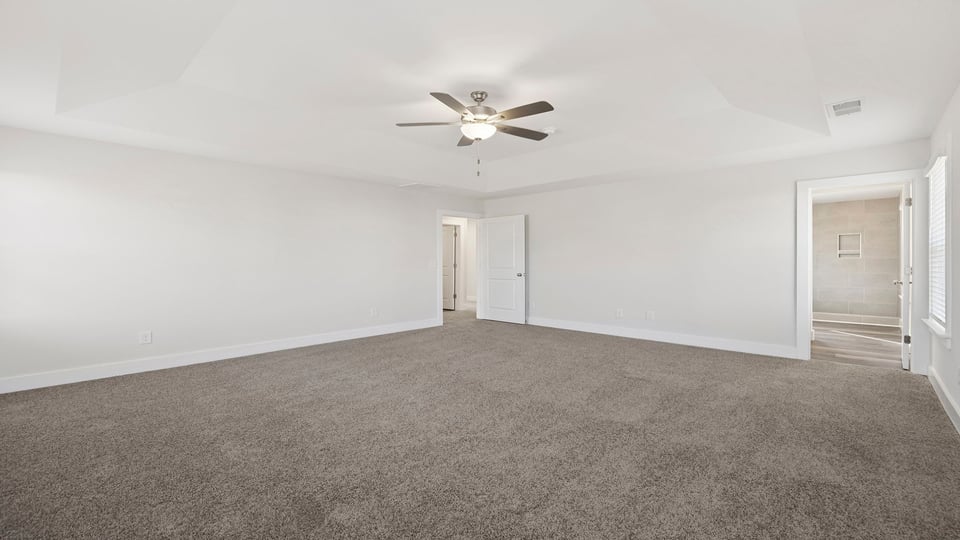 Primary bedroom with carpet and windows.