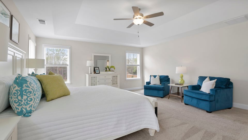 Primary bedroom with carpet and windows.