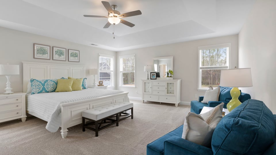 Primary bedroom with carpet and windows.