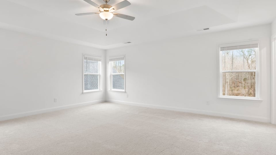 Primary bedroom with windows and carpet.