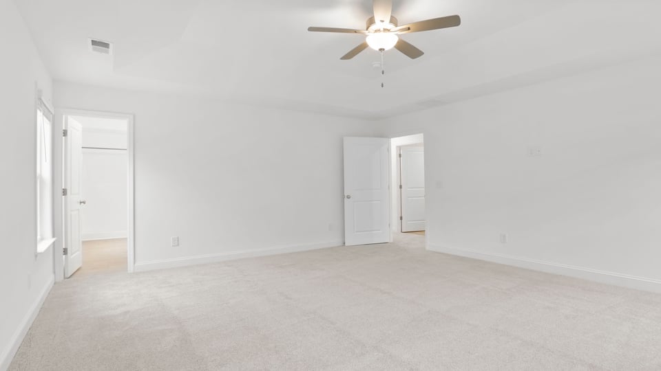 Primary bedroom with carpet and window.
