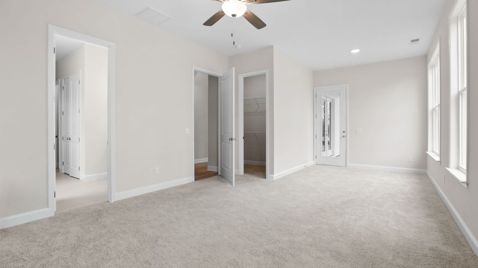Primary bedroom with carpet and windows.