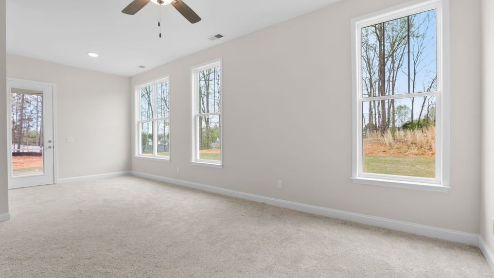 Primary bedroom with carpet and windows.