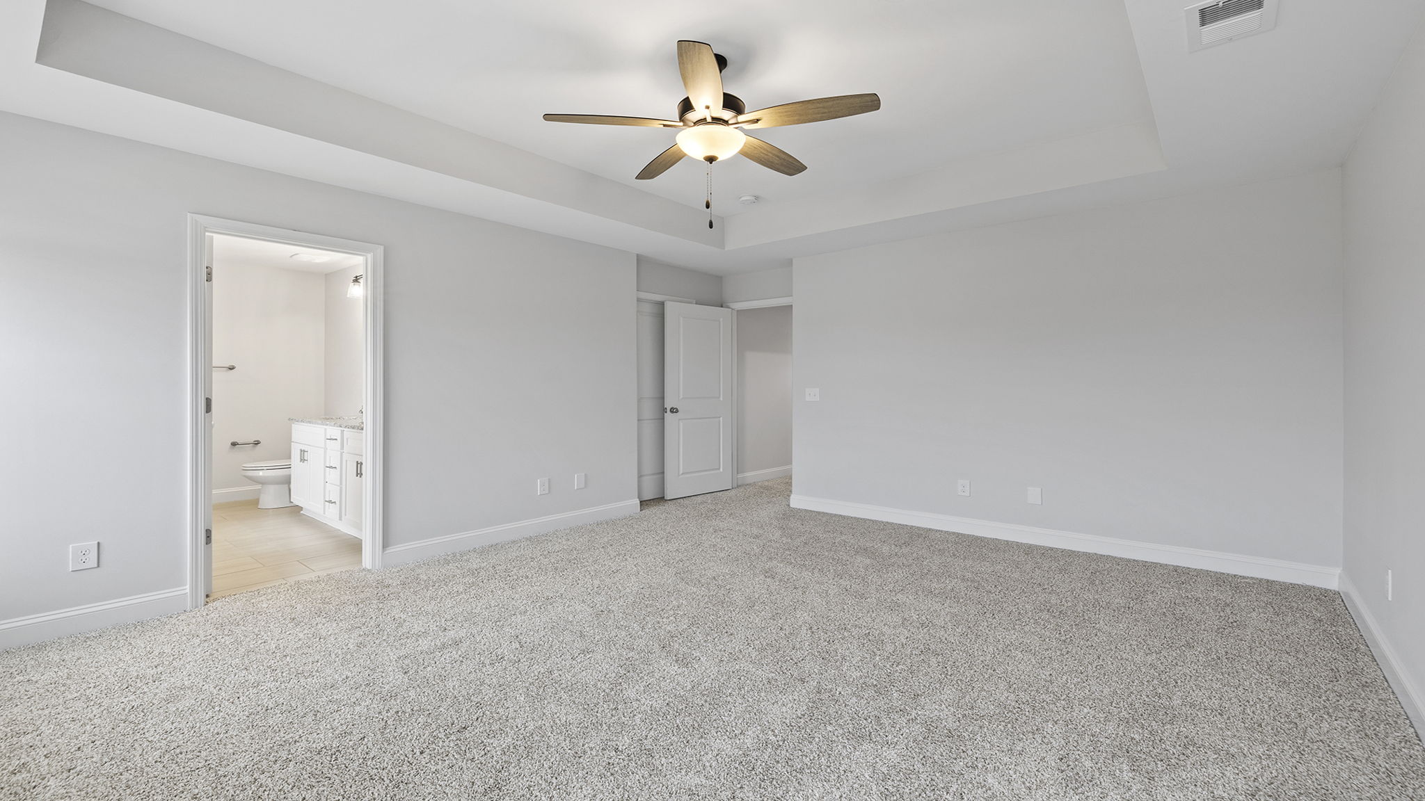 Primary bedroom with carpet and windows.