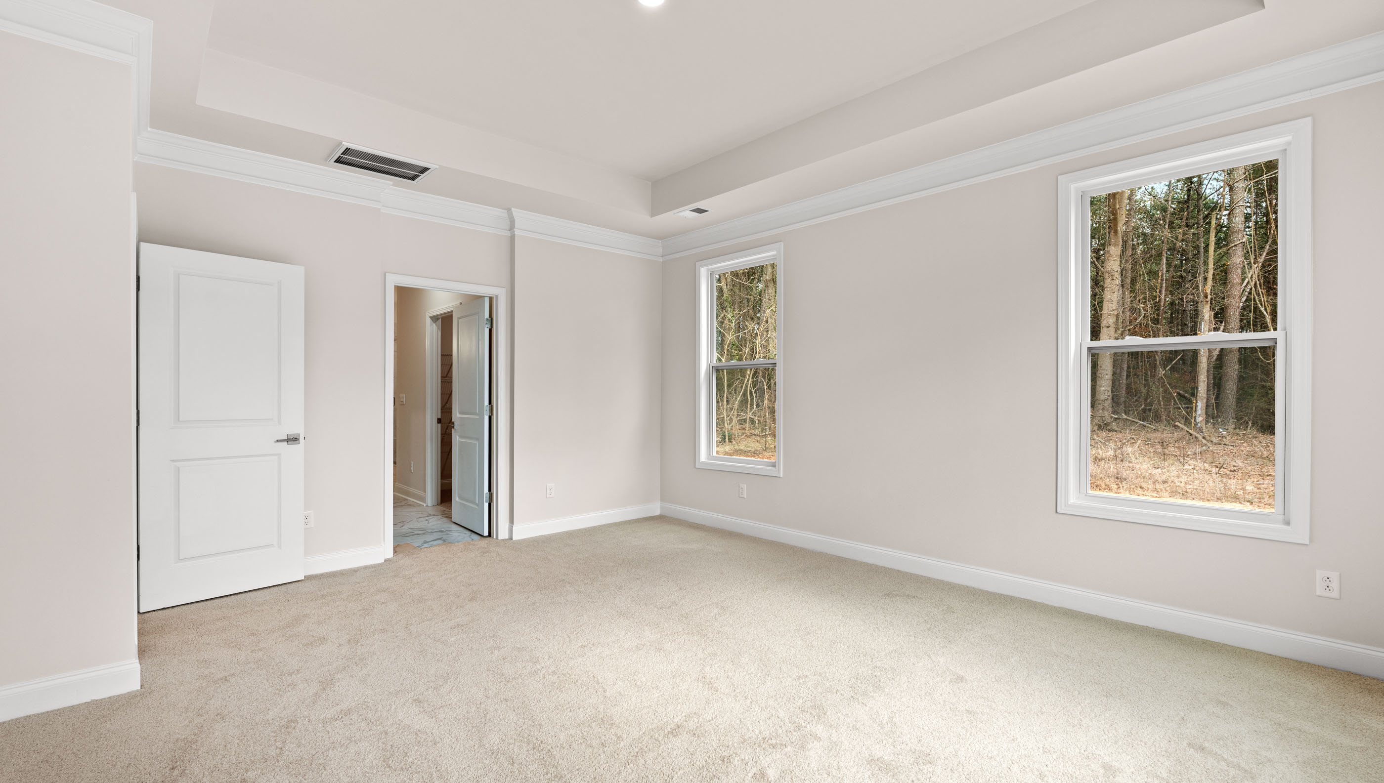 Primary bedroom with carpet and window.
